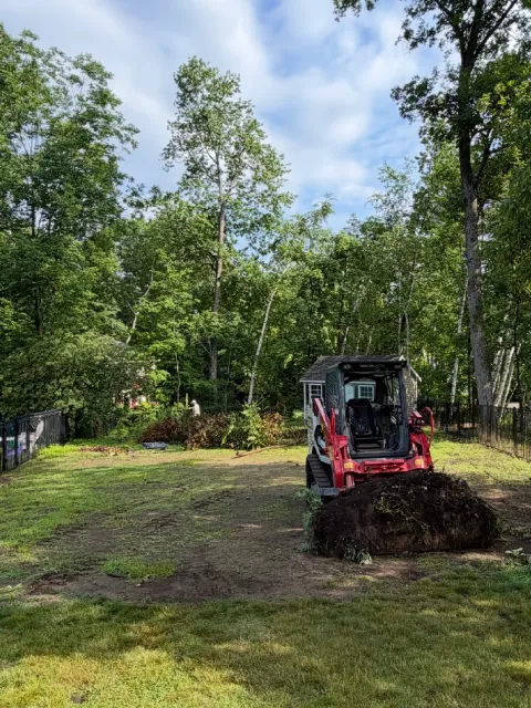 Excavator moving soil in garden setting