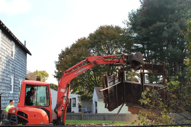 An excavator lifting a large piece of wood