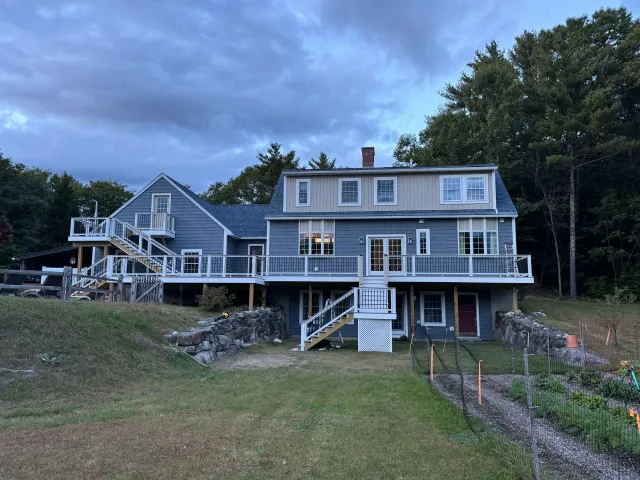 A large house with a large deck in the middle of a field.
