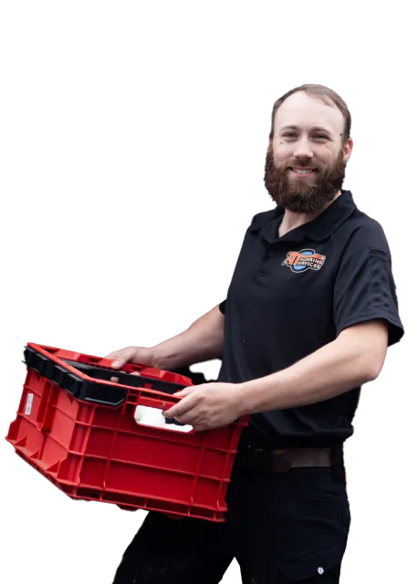 A man with a beard smiling while holding a red plastic storage crate, wearing a black polo shirt with a company logo.