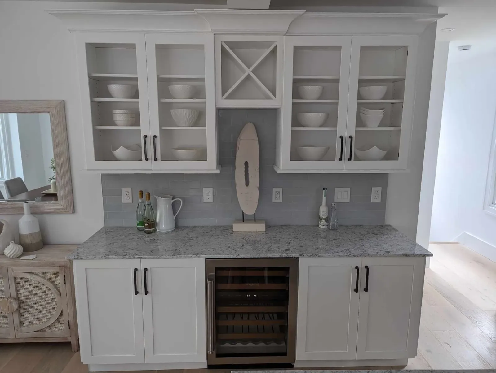 A kitchen with white cabinets, granite counter tops, and a wine cooler.