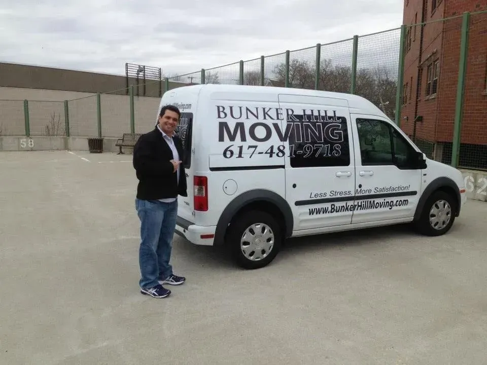 A person stands in a parking lot next to a white van branded with the