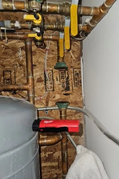 Copper plumbing pipes with valves and red tool