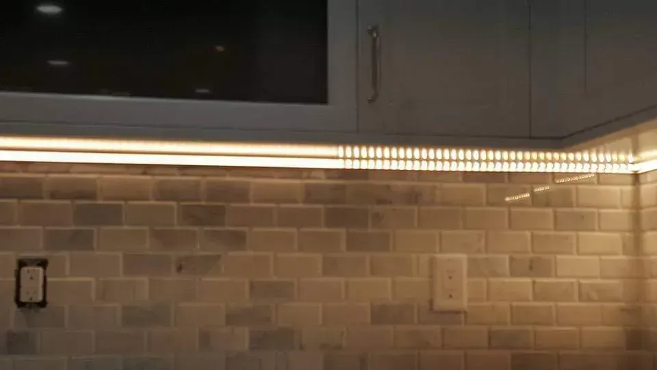 A kitchen with a brick wall and cabinets and a light on the wall.