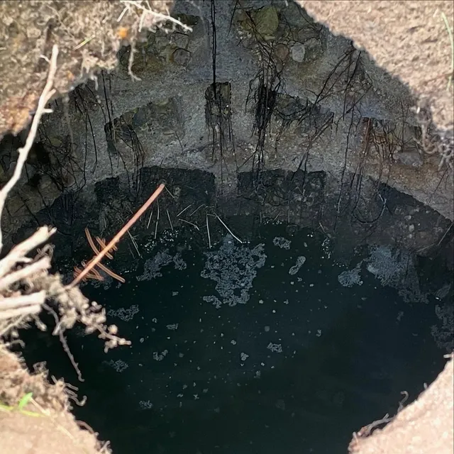 Here’s a look inside of a drywell. Drywells are an old style leaching system common in this area between the 1940s-1970s. They are typically 4-8 feet round and deep. This one has a crushed stone floor with walls made of stacked cinder block surrounded by crushed stone, with a concrete slab top. Most drywell systems have 2-4 drywells in a series.