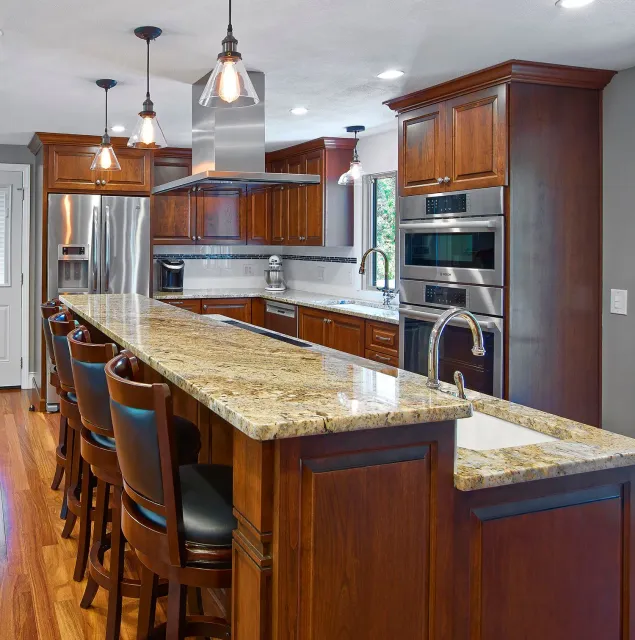 Modern kitchen with dark wood cabinets, granite island, stainless steel appliances, and pendant lights.