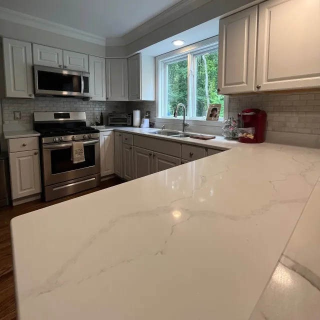 Bright modern kitchen with white cabinets, stainless appliances, and a marble island countertop