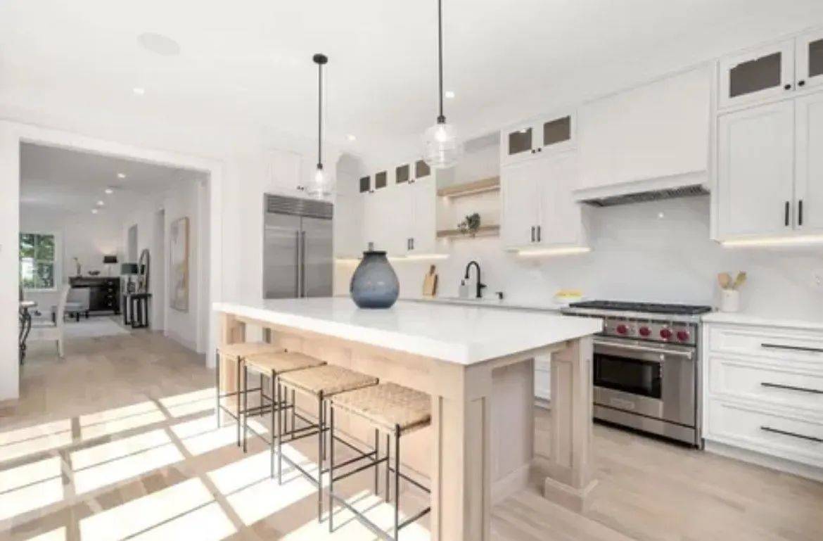 A kitchen with white cabinets, stainless steel appliances, and a large island.