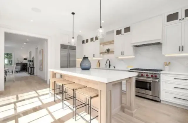 A kitchen with white cabinets, stainless steel appliances, and a large island.