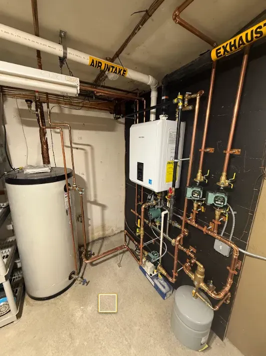 Utility room with water heater, boiler, exposed copper pipes, and labeled air intake/exhaust ducts