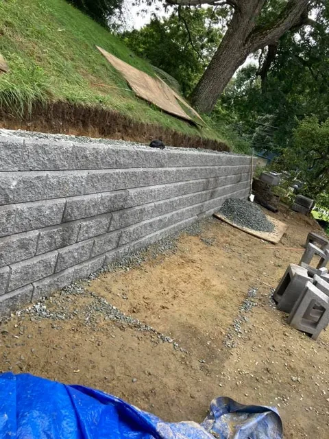 Segmental block retaining wall under construction on a sloped yard