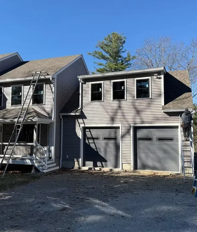 Gray two-story house with attached two-car garage and small front porch under clear blue sky