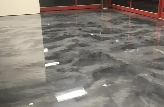 Artistic silver and charcoal metallic epoxy flooring with custom resin swirls for a high-end luxury interior finish.