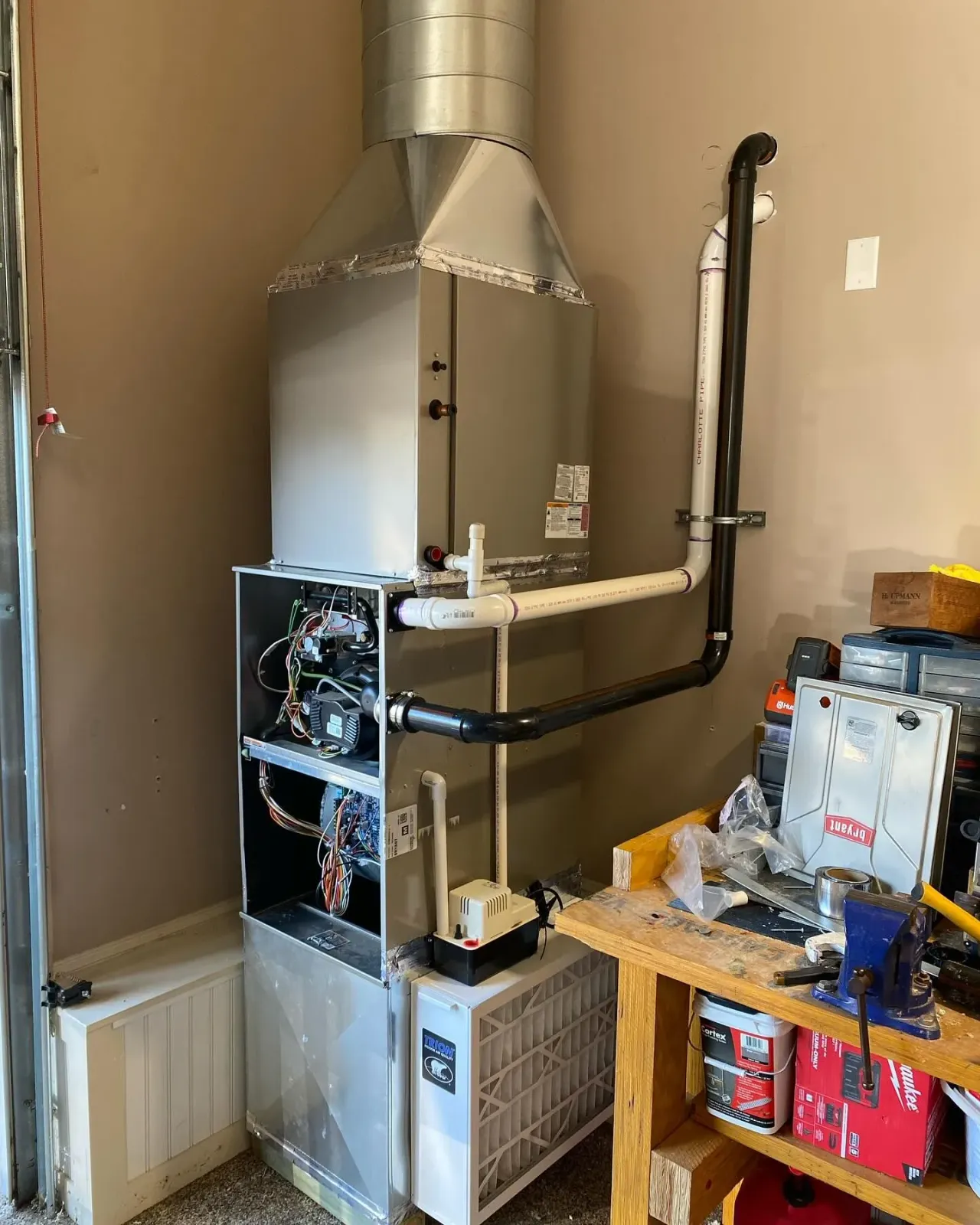A gas heater is sitting in a garage next to a wooden workbench.
