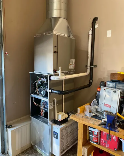 A gas heater is sitting in a garage next to a wooden workbench.