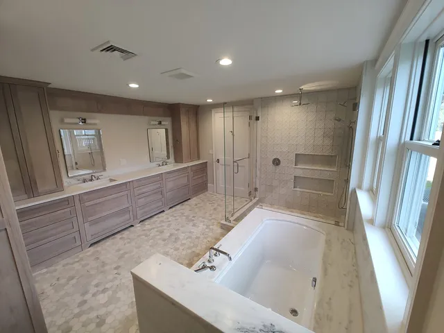 Renovated master bathroom with a double vanity, soaking tub and glass walk-in shower