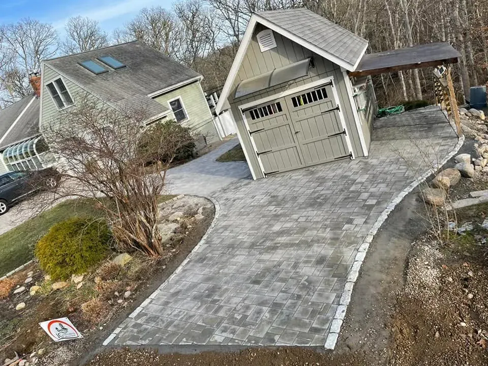 Finished gray paver driveway connecting a home and detached garage