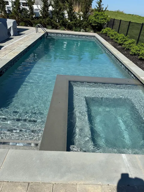 A clear pool with an attached spa and bluestone coping