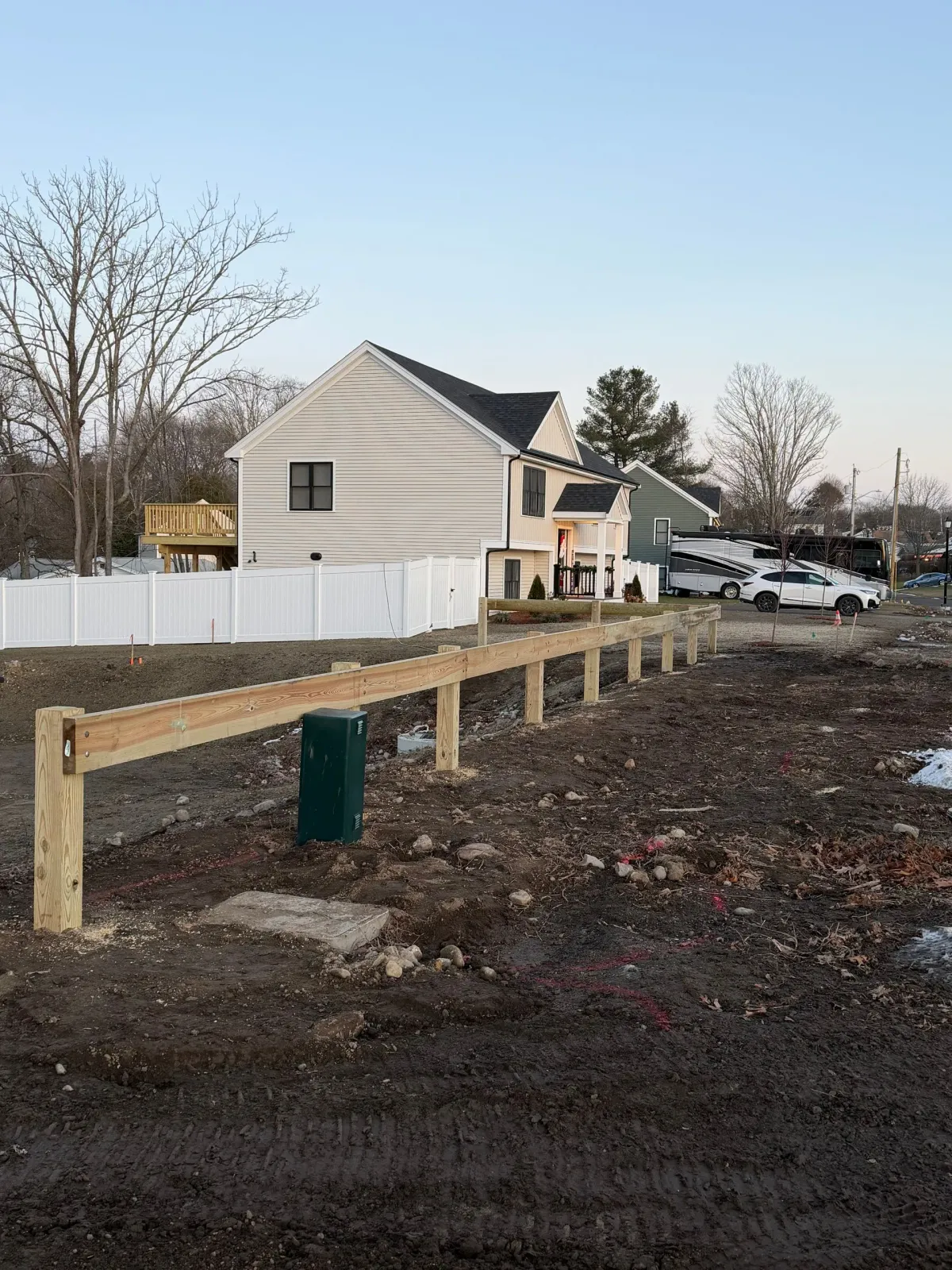 Wooden fence under construction in front of a house. Bare ground.
