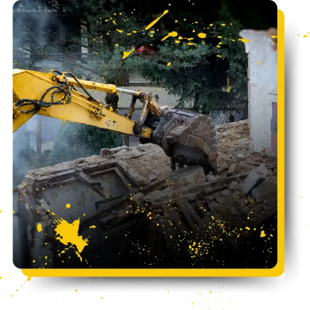 A yellow excavator is demolishing a building.