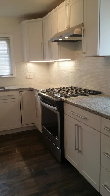 Renovated kitchen with tile backsplash and granite counters