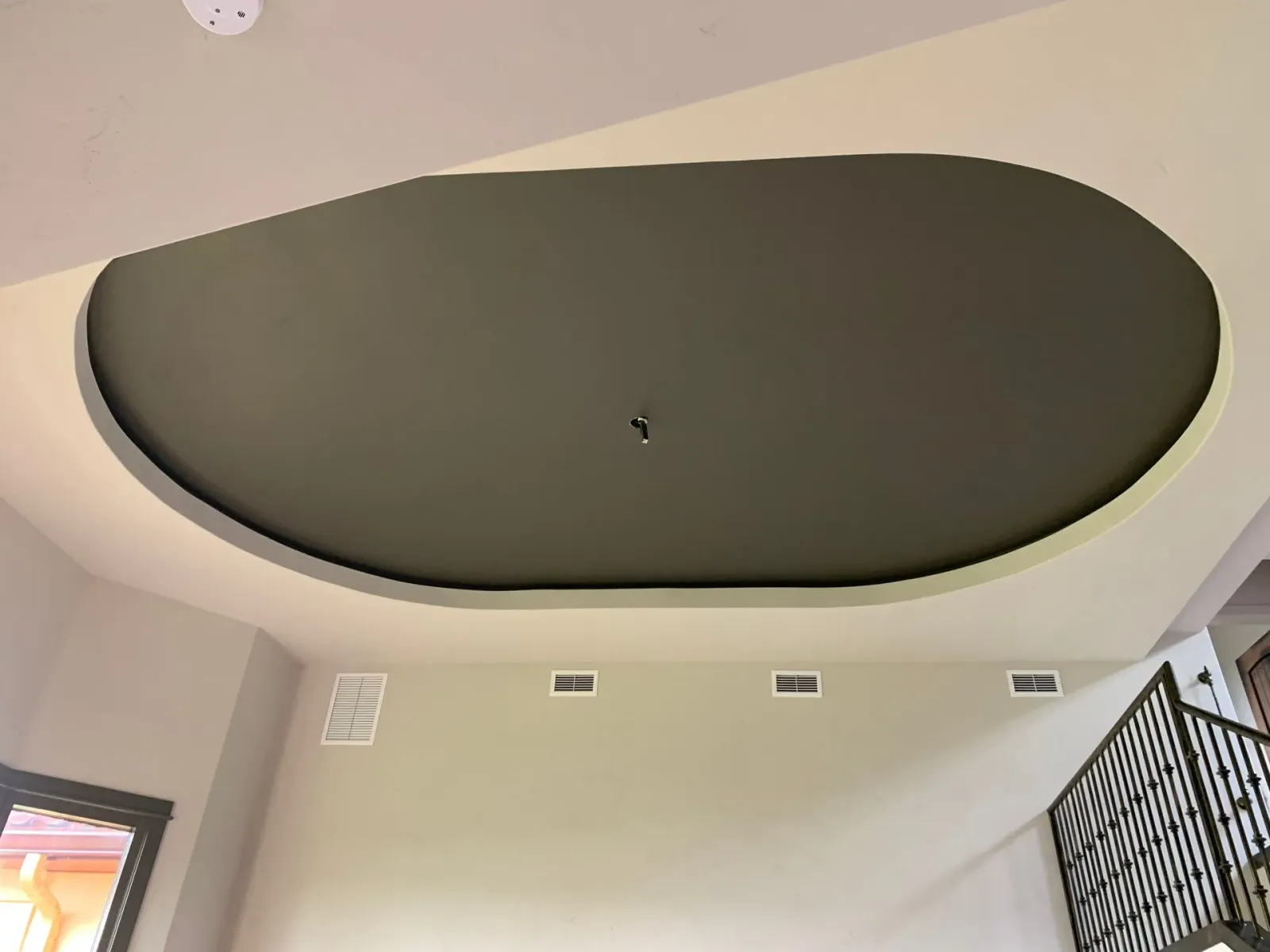 A ceiling in a room with a staircase in the background