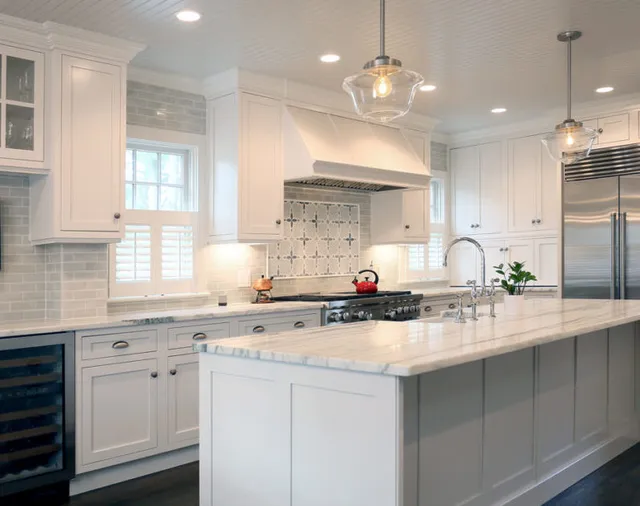 Photo of kitchen with marble island and stainless appliances - Woodland Builders, South Shore MA.