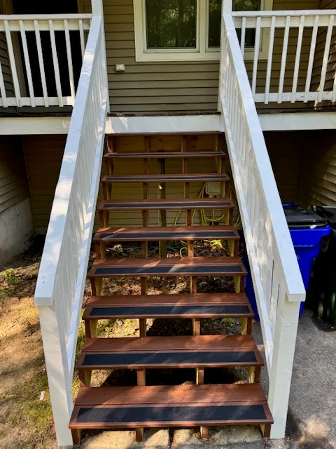 Close view of rebuilt exterior stairs with white railings in Goffstown