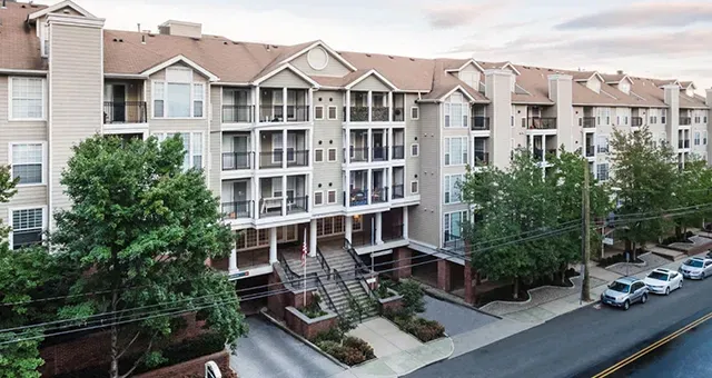 An aerial view of a large apartment building with cars parked in front of it.