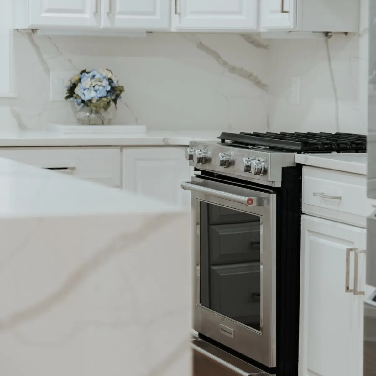 Completed white kitchen with quartz waterfall counter and slab backsplash