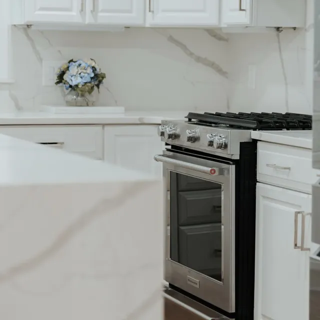 Completed white kitchen with quartz waterfall counter and slab backsplash