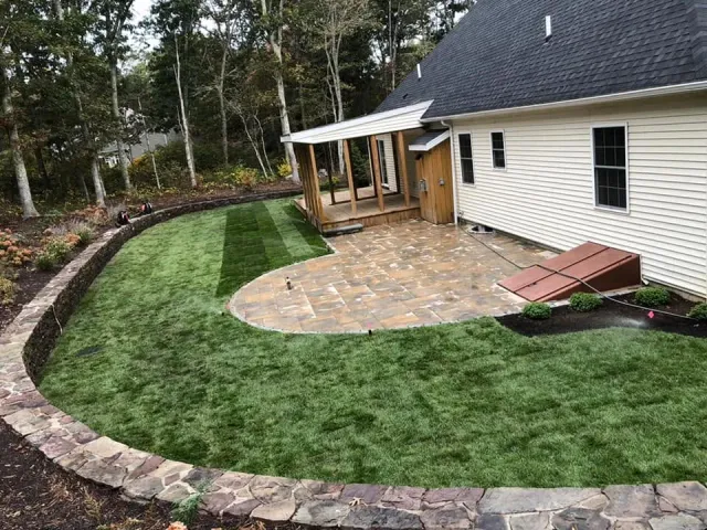 Finished curved paver patio beside a newly landscaped lawn
