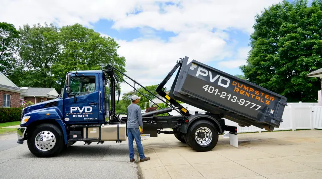 Driver operating the controls during a dumpster delivery