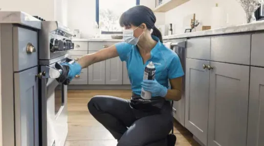 Merry Maids team member cleaning oven
