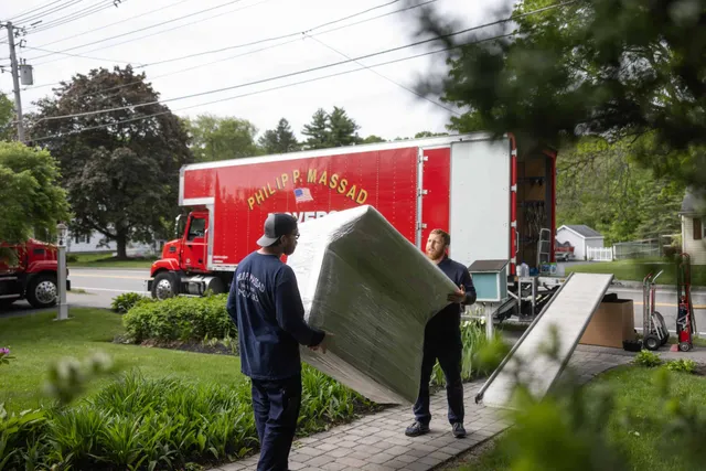Two men unloading a large box from a truck.