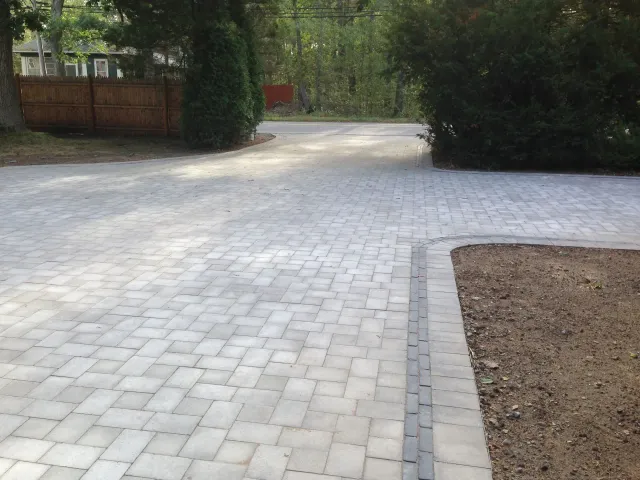 A brick driveway with a fence in the background
