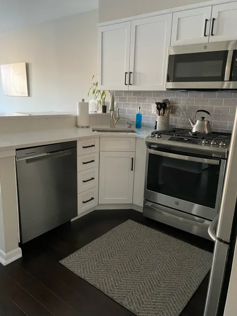 A kitchen with stainless steel appliances and white cabinets.
