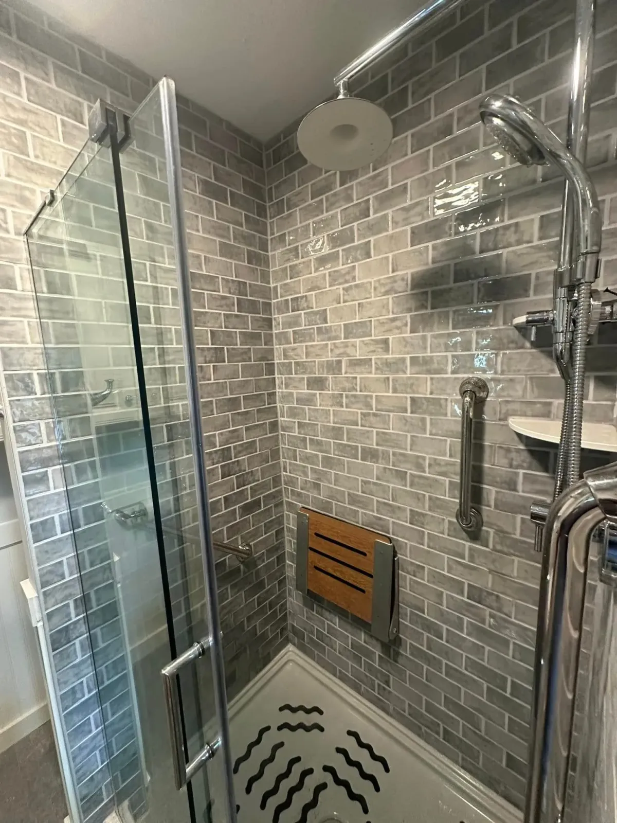 A bathroom with a walk in shower with a wooden seat.