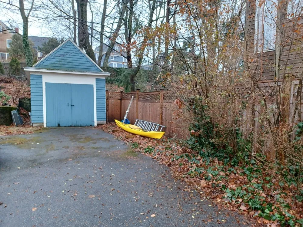 Existing wood fence line along a driveway before replacement