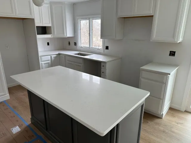 A kitchen with white cabinets and a large island in the middle.