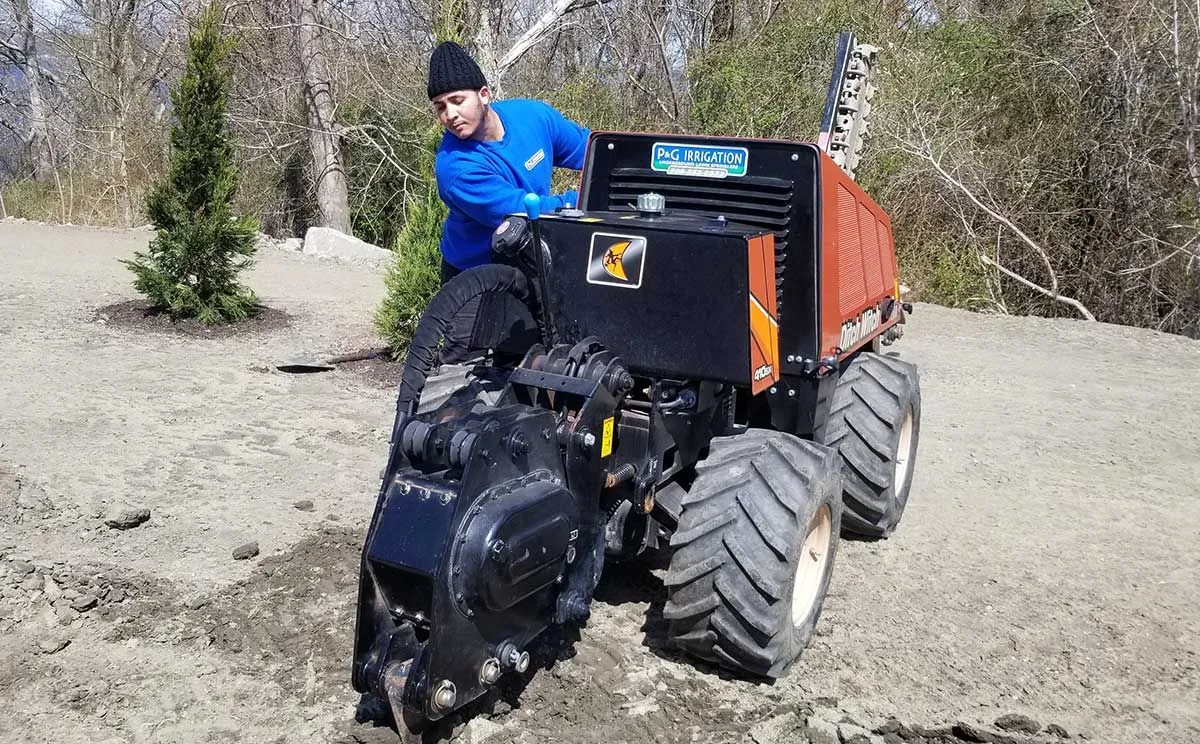 A man is driving a tractor on a dirt road.