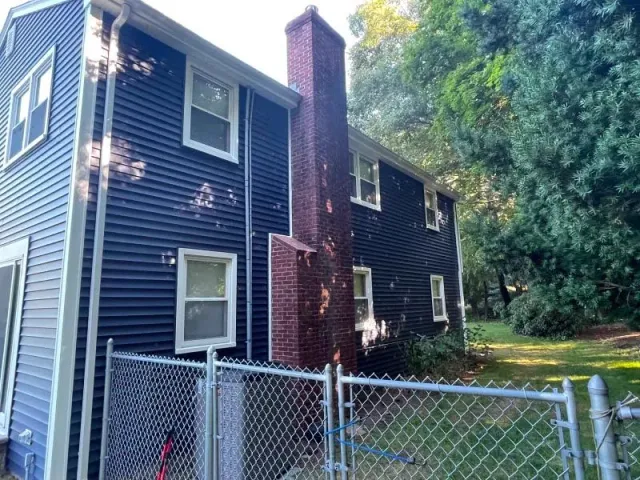 A blue house with a chain link fence in front of it