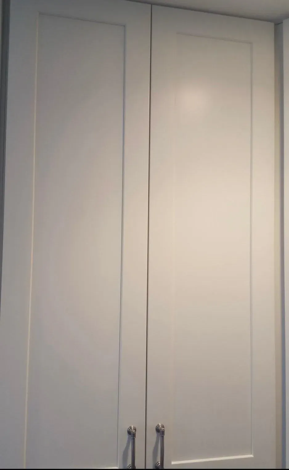 White double closet doors with silver handles in a room.