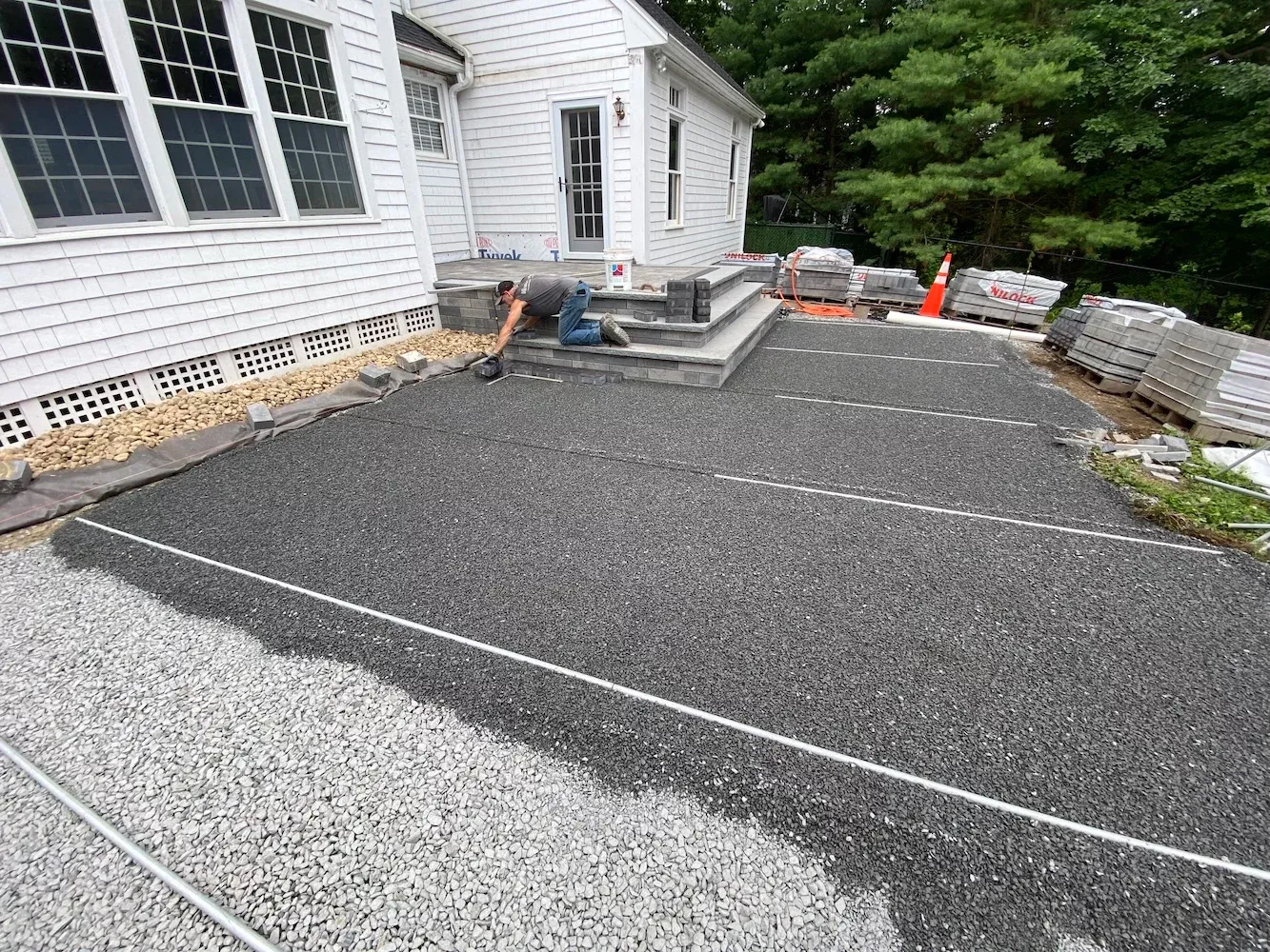 Paver patio base preparation with compacted stone, screed rails, and foundation drainage during installation, Southeastern MA