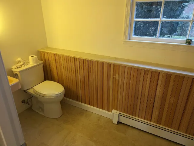 A bathroom with a toilet , sink and window.