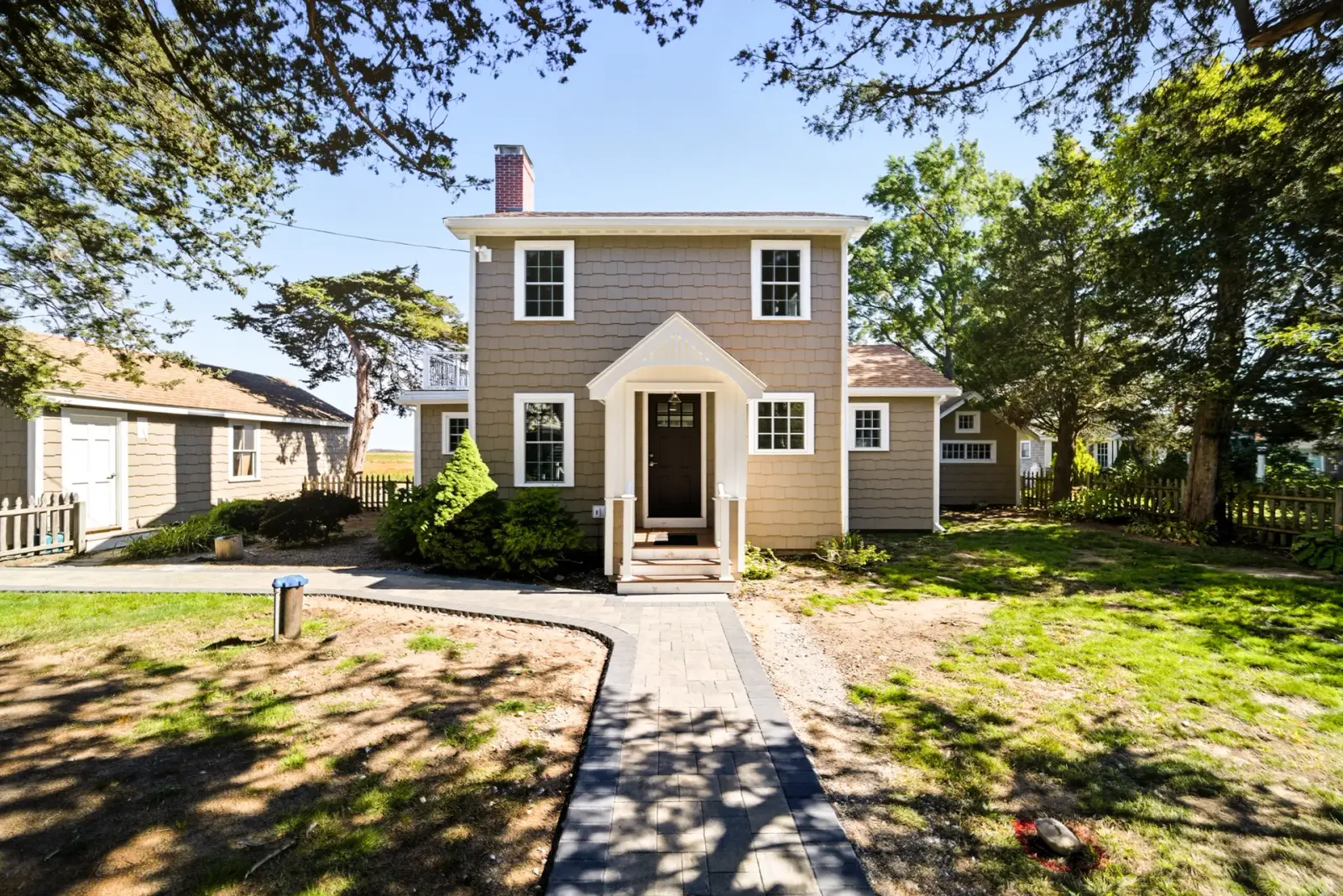Exterior view of a newly renovated two-story home in West Newbury, MA, featuring updated siding, a new roofline, and landscaped front yard with a stone pathway, highlighting Bradford Construction's design-build expertise.
