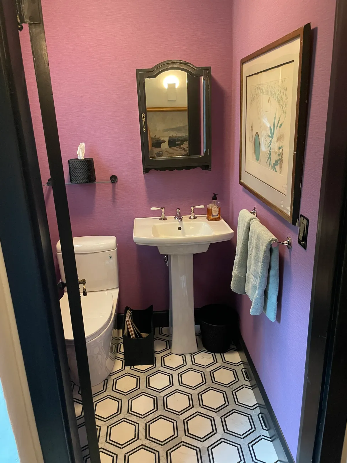 A bathroom with purple walls , a sink , toilet and mirror.