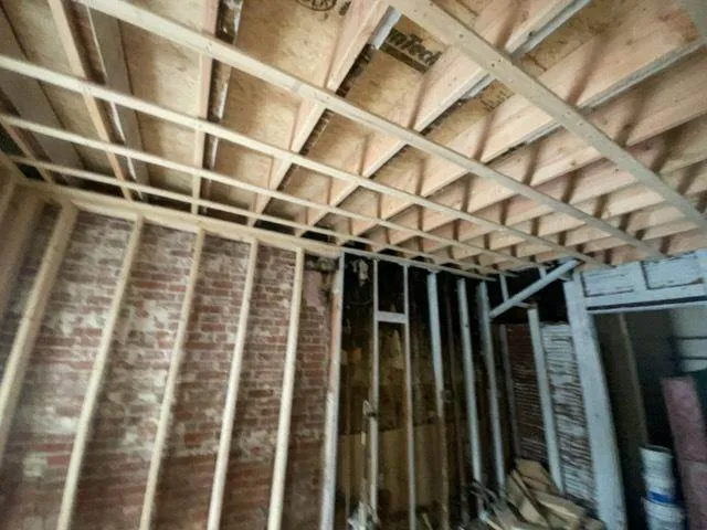 Property rehab with exposed brick, ceiling framing, and rough carpentry in progress