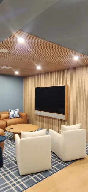 A living room with a couch , chairs , and a flat screen tv.