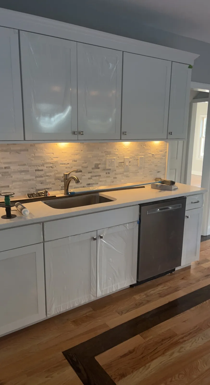 Remodeled kitchen with white cabinets and refinished hardwood flooring